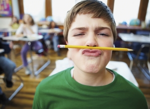 jeune garçon jouant avec un crayon en classe